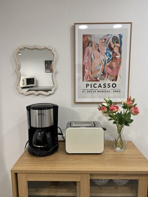 A kitchen counter with a coffee maker, toaster, and a vase of flowers. - ARA125 (Seoul)