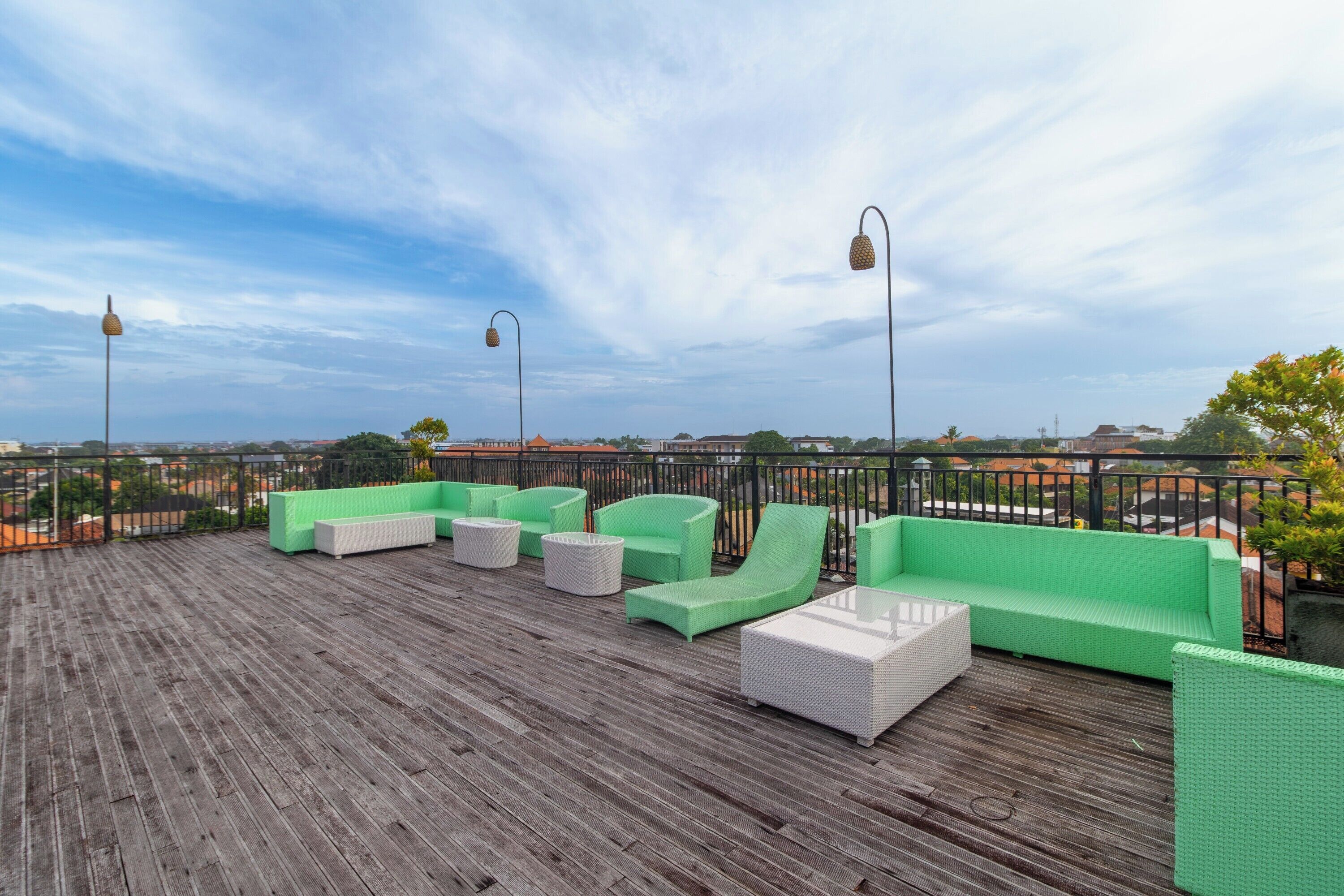 A rooftop deck with green seating and a view of the city.