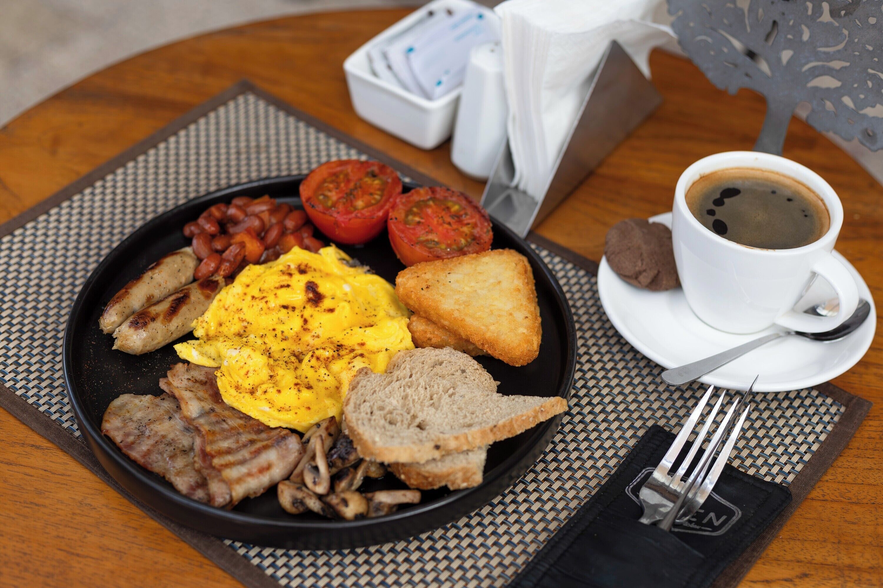 Un plato de desayuno con huevos, tocino, tomates, tostadas y frijoles.