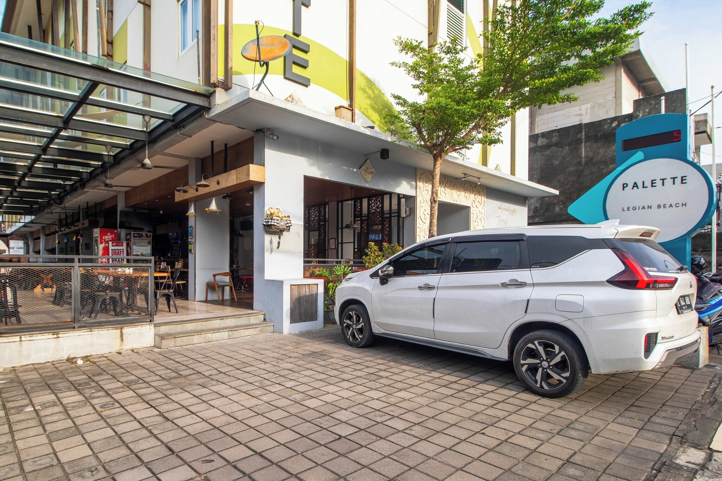 A white car parked in front of a building with a sign that reads 'PALETTE LEGIAN BEACH'.