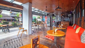 An indoor dining area with wooden tables, red cushioned seating, and a view of the street outside. - Palette Legian Beach (Legian)
