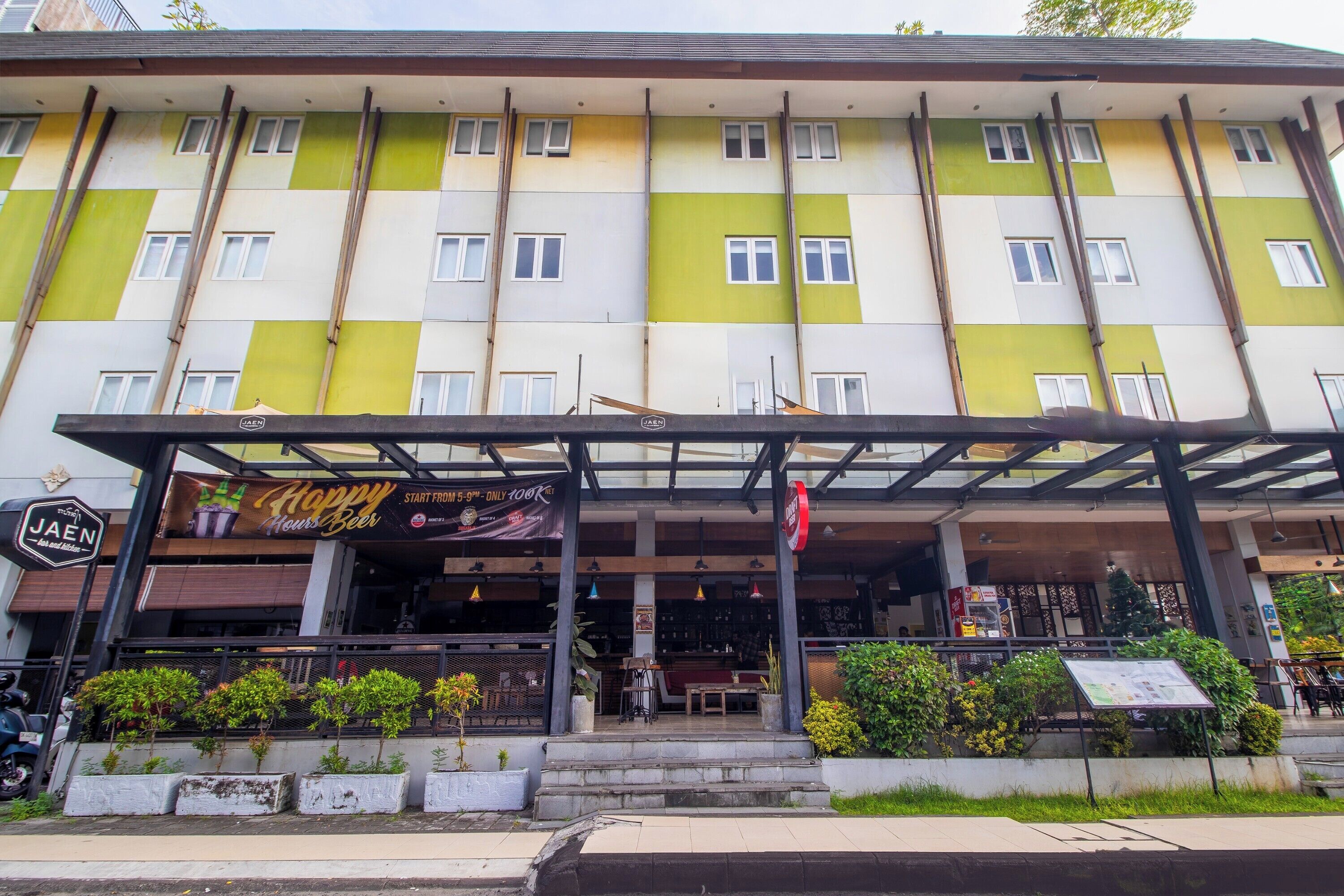 Un edificio de varios pisos con restaurante en la planta baja, mesas al aire libre y un cartel que indica un límite de permanencia de 5 a 9 horas.