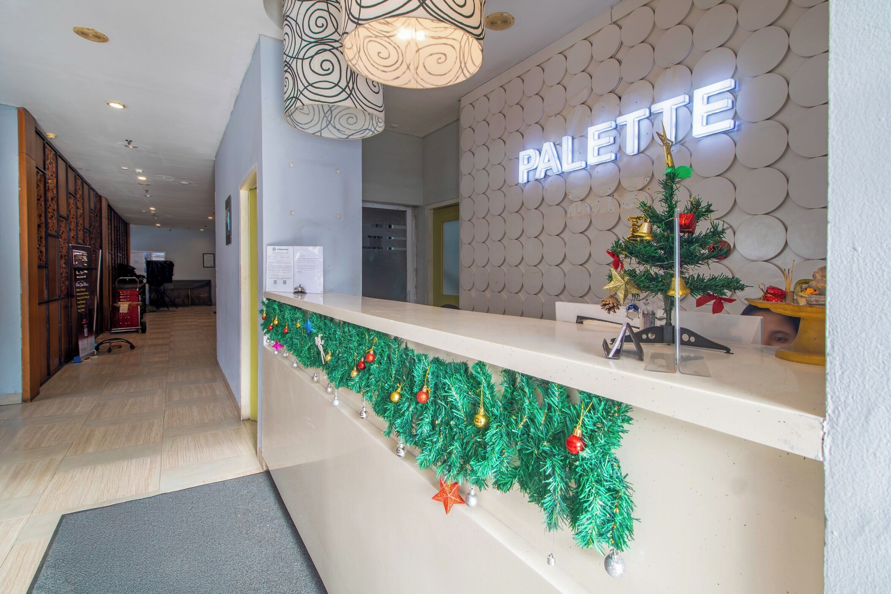 A hotel reception area with a 'PALETTE' sign, a Christmas tree, and a decorative garland.