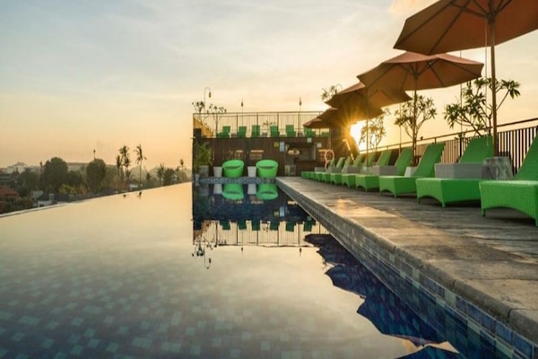 Una piscina al aire libre, sombrillas, sillones reclinables de piscina