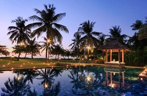 A serene pool area with palm trees and a gazebo at dusk. - Villa Hanani (Jimbaran)
