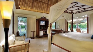 Ein Schlafzimmer mit Baldachinbett, Fernseher und Blick ins Freie.