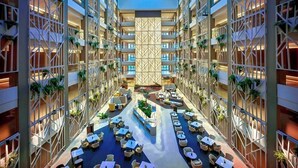 Een moderne hotelatrium met meerdere verdiepingen, een centrale open ruimte met zitplaatsen en een decoratief muurpatroon.