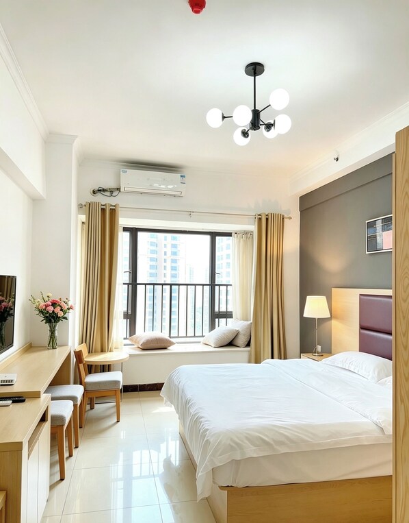 A hotel room with a bed, desk, chair, and a view of buildings through the window.