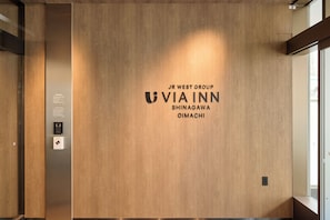 A wooden wall with the text 'JR WEST GROUP VIA INN SHINAGAWA OIMACHI' and a small electronic device below it. - JR WEST GROUP VIA INN SHINAGAWA OIMACHI (Tokyo)