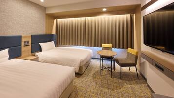 A hotel room with two beds, a small table, a chair, a TV, and a large window with curtains.