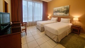 Una habitación de hotel con dos camas, televisión, escritorio y un cuadro en la pared.
