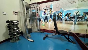 Une salle de sport équipée de matériel d’exercice, avec un miroir et un sol bleu.