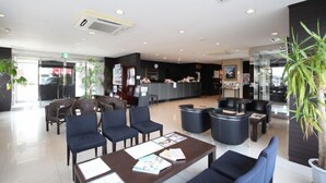 A modern hotel lobby with seating areas, a reception desk, and a large potted plant. - Az Inn Higashiomi Notogawa Ekimae (Higashiomi)