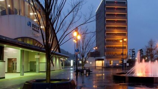 A modern building with a curved facade and a rectangular structure with balconies. - Az Inn Higashiomi Notogawa Ekimae (Higashiomi)