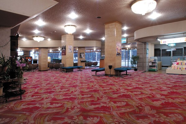 A spacious lobby with a patterned carpet, seating areas, and a visible store. - Kinpokan (Toba)