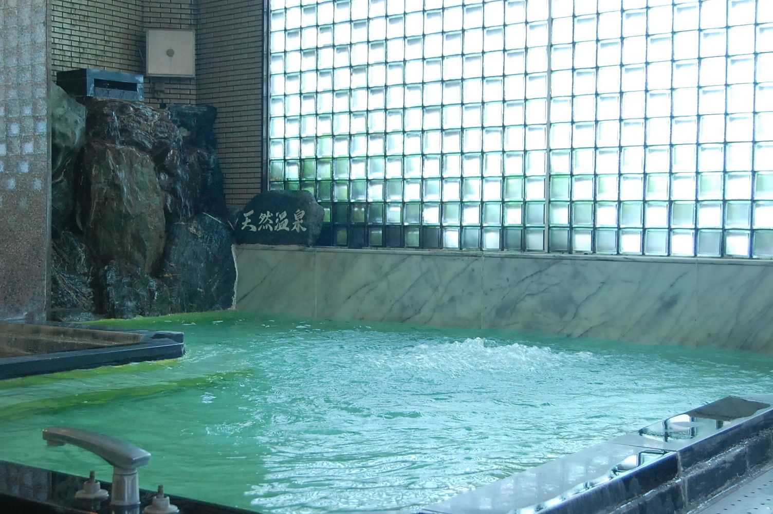 A large indoor water feature with a rocky waterfall and a tiled wall.