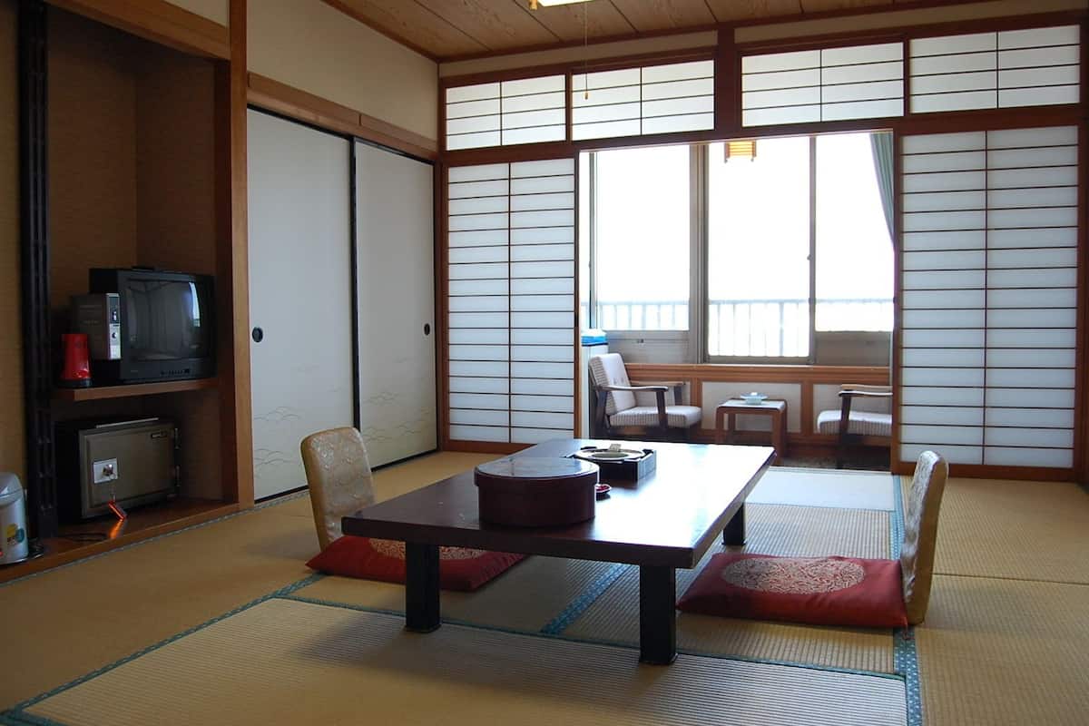 Una habitación japonesa tradicional con suelo de tatami, una mesa baja y un sofá.