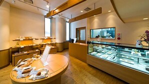 Un comptoir de boulangerie avec du pain et des viennoiseries, une vitrine remplie de produits de boulangerie, et un espace d’accueil avec un miroir et un vase.