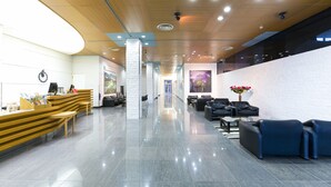 Un hall d’entrée moderne comprenant un comptoir d’accueil, un espace salon et un grand mur orné d’œuvres d’art.