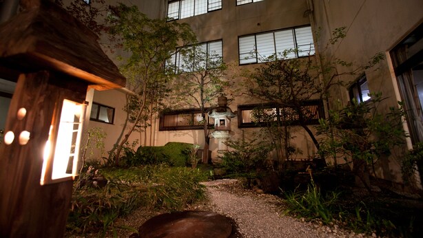 Un patio con un farol tradicional japonés, un farol de piedra y una pequeña pagoda.