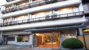 Un edificio de varios pisos con entrada a nivel de calle, grandes ventanales y un pequeño jardín.