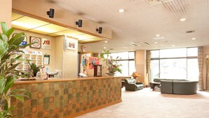 Zona de recepción con mostrador de check-in, asientos y ventanas amplias.