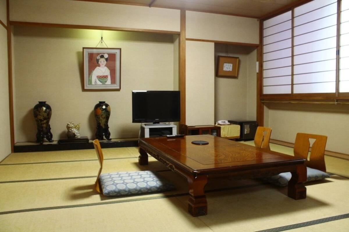 A traditional Japanese room with tatami flooring, a low wooden table, and a television.