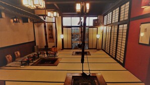 Um quarto japonês tradicional com esteiras de tatame, mesinhas baixas e portas deslizantes.