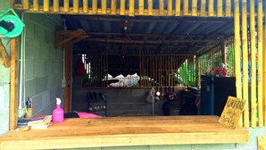 A rustic wooden structure with a bamboo fence, a wooden bench, and a sign indicating a 30kg service charge. - Sleepy Hut Pai (Pai)