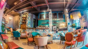 A modern bar area with a colorful tile wall, seating with cushioned chairs, and a visible bar counter. - Geminai Hotel & Cafe (Dong Hoi)