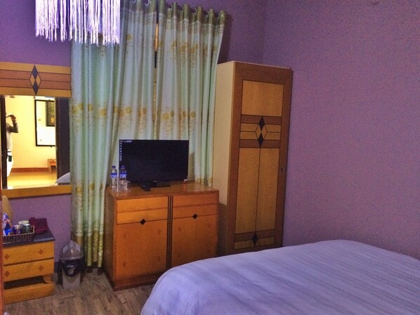 A hotel room with a bed, a wooden dresser, a television, and a wardrobe. - Geminai Hotel & Cafe (Dong Hoi)