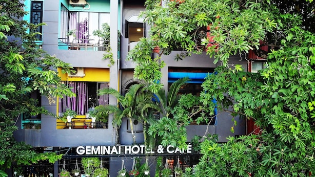 A multi-story hotel with outdoor seating and lush greenery. - Geminai Hotel & Cafe (Dong Hoi)