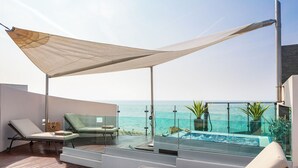 Un balcón moderno al aire libre con piscina infinita de cristal, sillones de descanso y plantas en macetas.