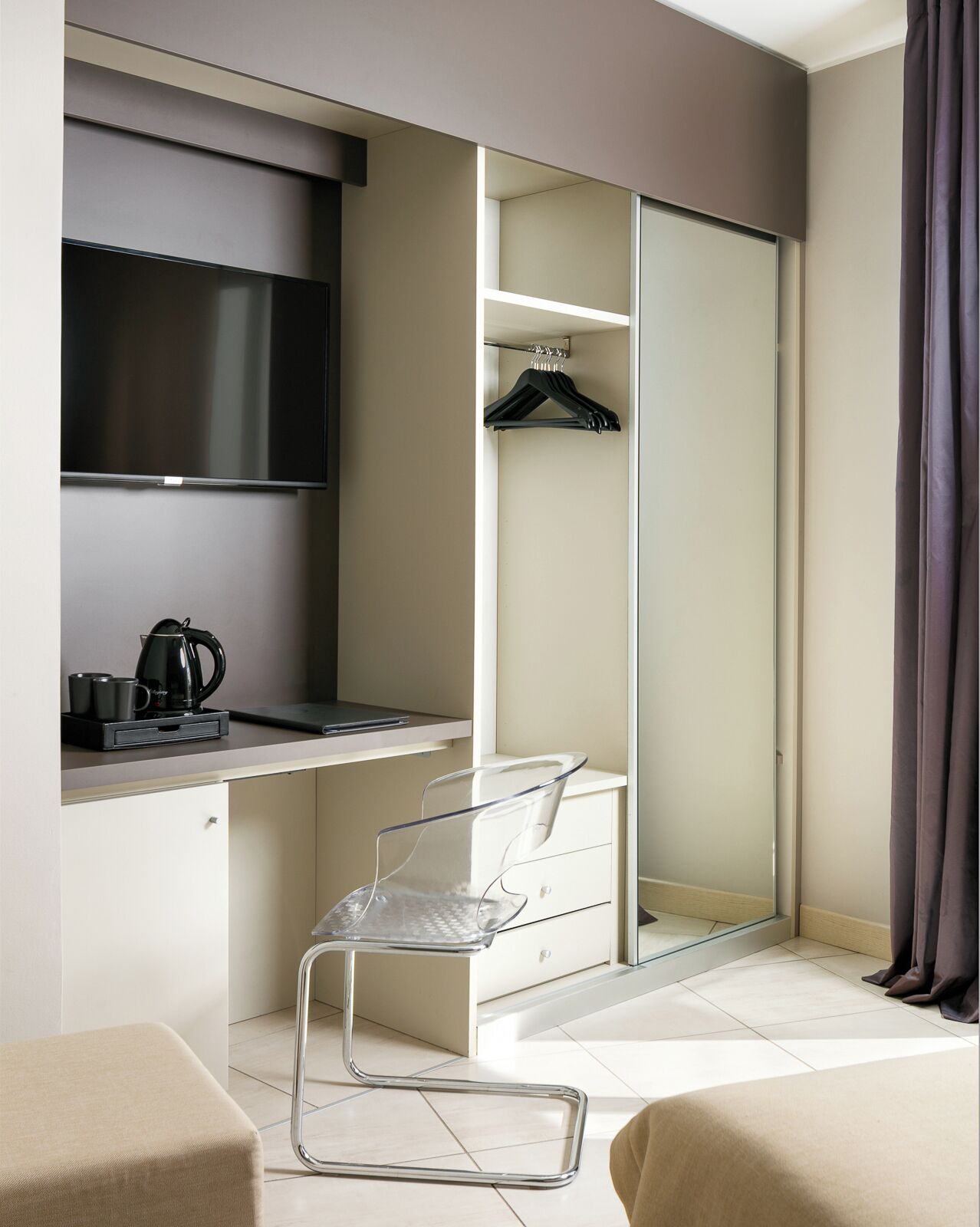 A modern hotel room with a desk, a chair, a wardrobe, and a mirror.