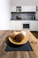 Una cocina moderna con armarios blancos, horno empotrado y cafetera.