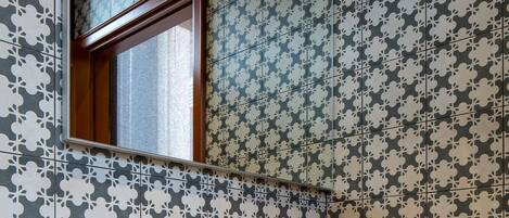 Un baño con un espejo grande, un lavamanos blanco y papel tapiz estampado.
