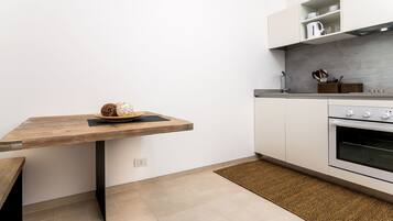 Une cuisine avec une table en bois, un four encastré et un plan de travail sur lequel sont rangés les ustensiles de cuisine.