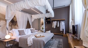 Quarto moderno com cama grande, mesas de cabeceira, abajur, televisão e guarda-roupa.