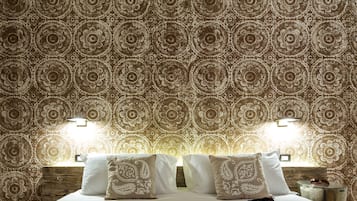 Ein Hotelzimmer mit gemustertem Wandpapier, einem Bett mit weißer Bettwäsche und zwei Wandleuchten.