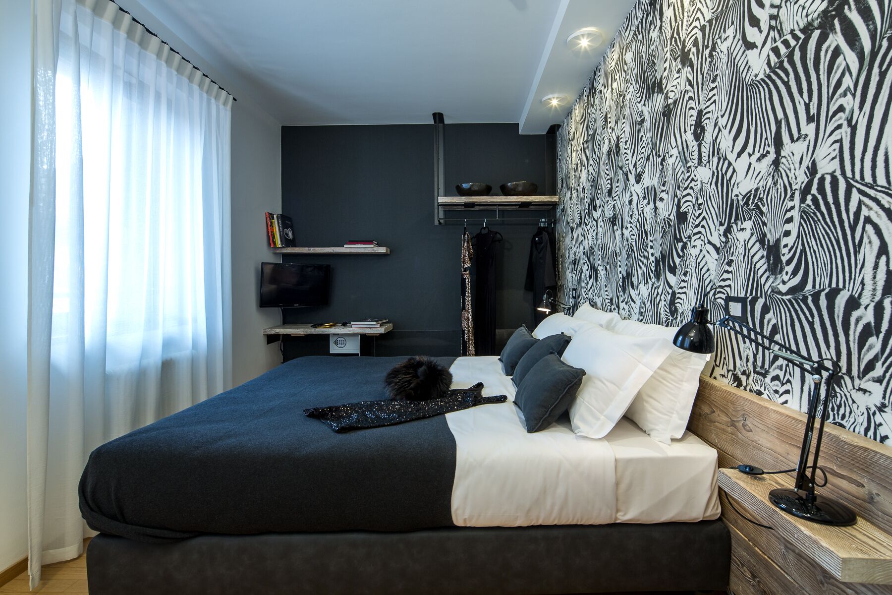 Ein modernes Schlafzimmer mit einem großen Bett, einem Fernseher, einem Kleiderschrank und einer Wand mit ZEBRA-Muster.
