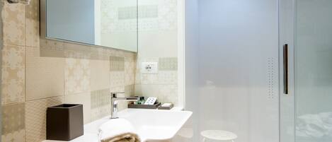 A modern bathroom with a large mirror, a white sink, and a glass shower enclosure.