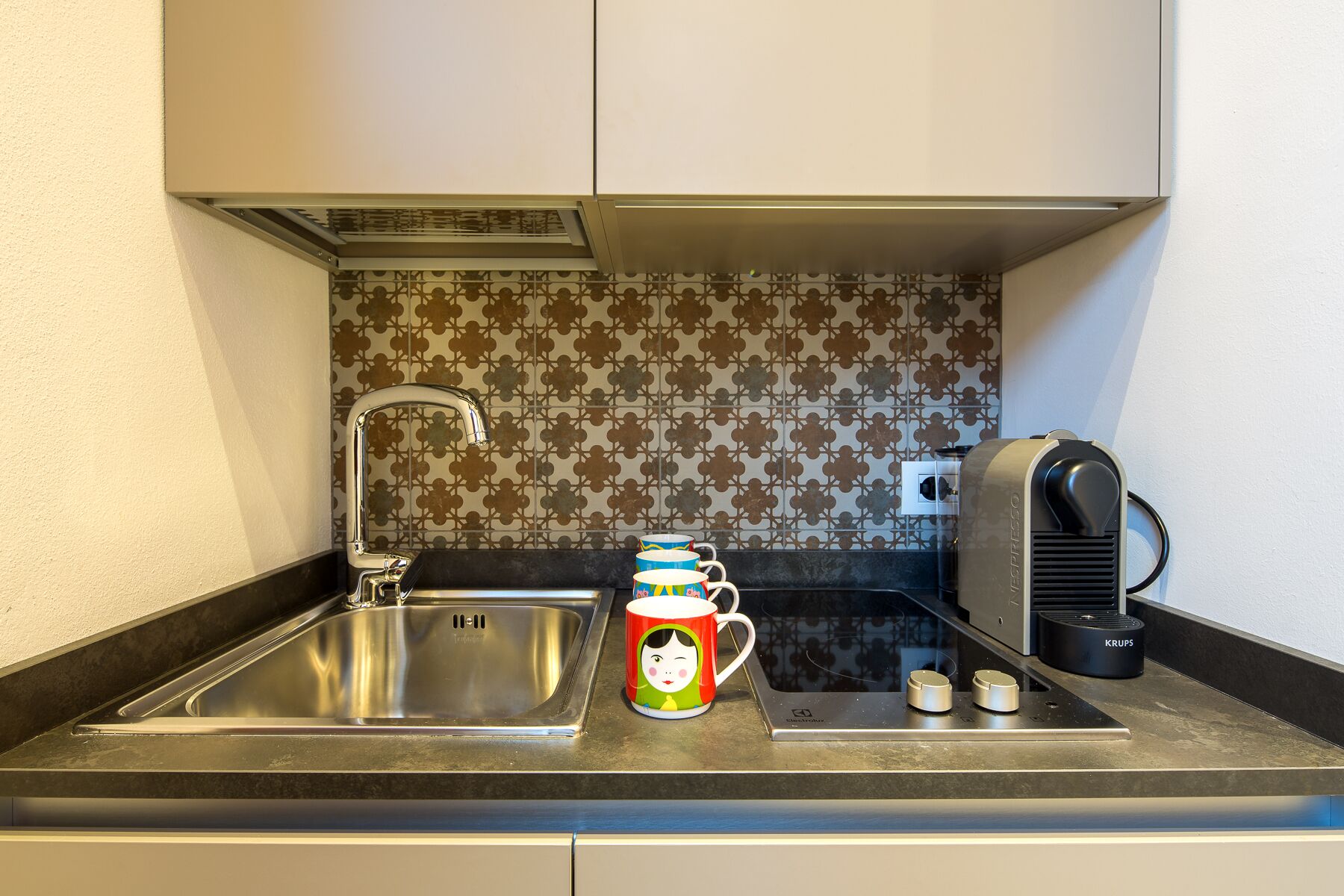 A kitchen with a stainless steel sink, a coffee machine, and a decorative mug.