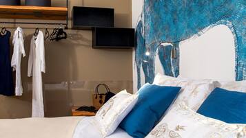 Een slaapkamer met een bed, kussens, een televisie en een kledingrek.