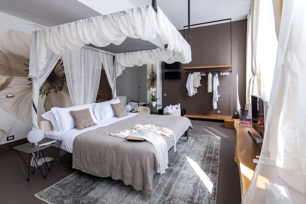 Een moderne slaapkamer met een groot bed, een nachtkastje, een stoel, een televisie en een kledingkast.