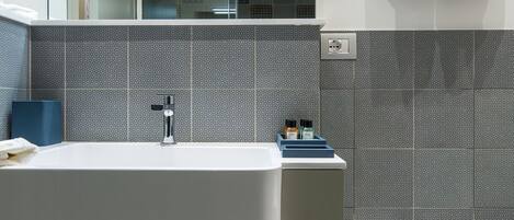 Un baño moderno con un espejo grande, un tocador doble y una bañera independiente.