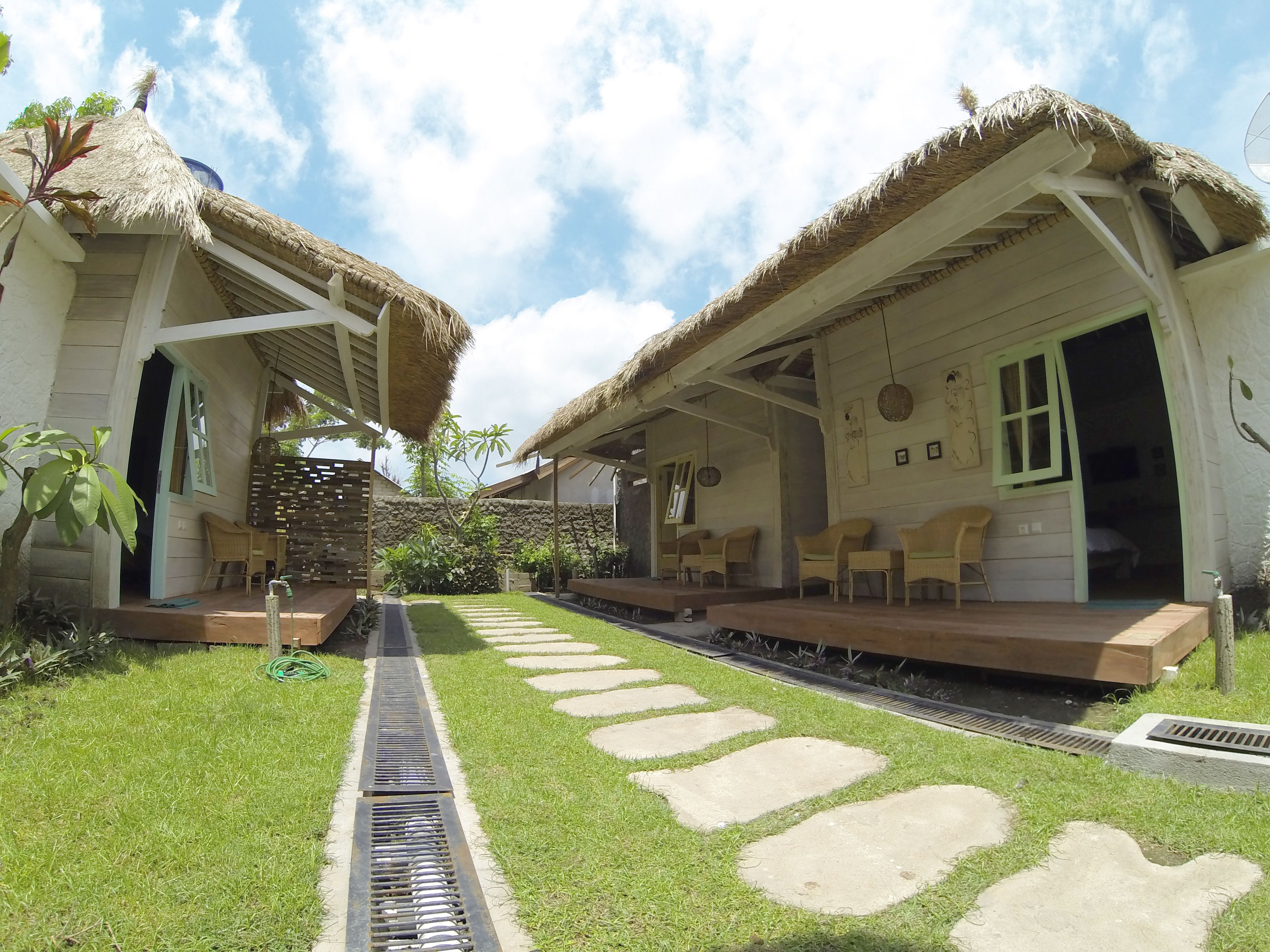 A bungalow with a thatched roof, a stone pathway, and a small garden.