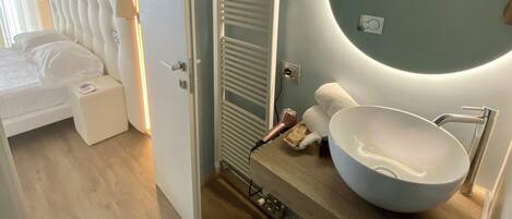 A modern bathroom with a large oval sink, a round mirror, and a towel rack.