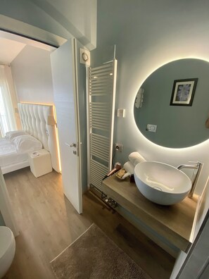 Un baño moderno con un lavabo ovalado grande, un espejo redondo y un perchero para toallas.
