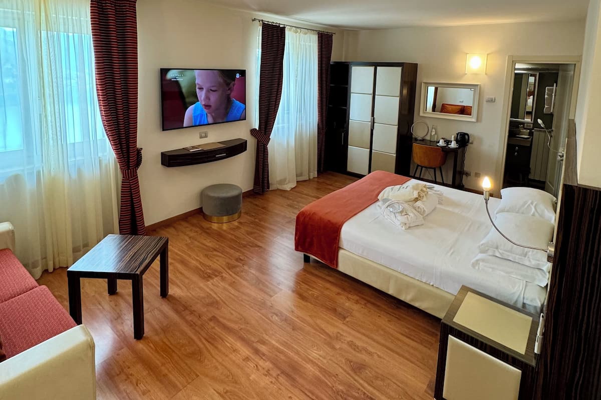 Ein Hotelzimmer mit einem Bett, einem Fernseher, einem Schreibtisch, einem Stuhl und einem kleinen Tisch.