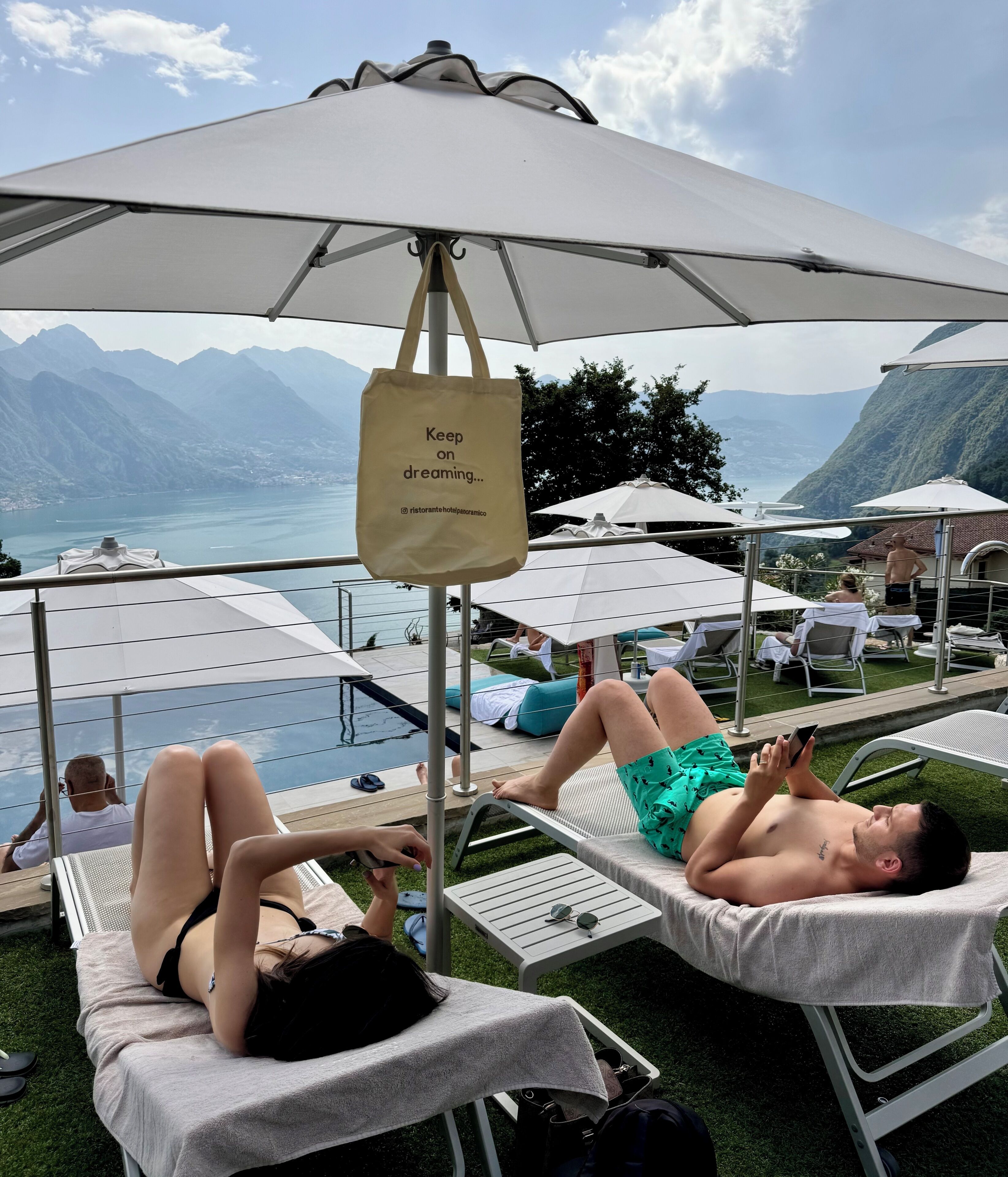 A poolside area with lounge chairs, umbrellas, and a sign that reads "Keep on dreaming...".